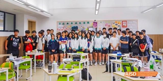 A large group of Guangzhou Huamei International School students posing for a photo in their classroom at the end of a lesson.