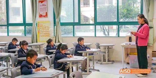 Guangzhou Huamei International School students quietly studying and writing at their desks in a classroom.