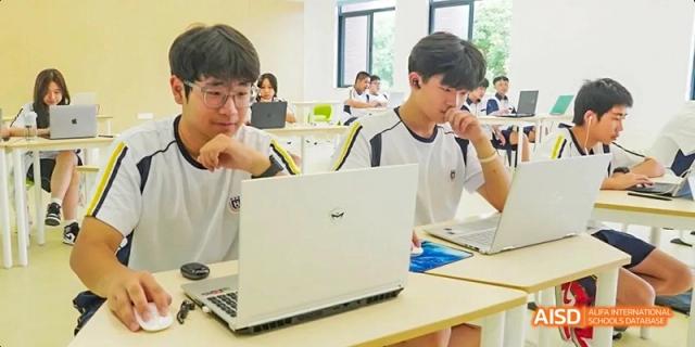 Two Guangzhou Huamei International School students using a laptop for a class or project at their desk.