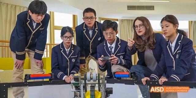 Guangzhou Huamei International School students working together on a robotics or engineering project, with one student controlling a device.