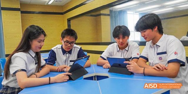 Two Guangzhou Huamei International School students collaborating on a project using tablet computers at a uniquely shaped desk.