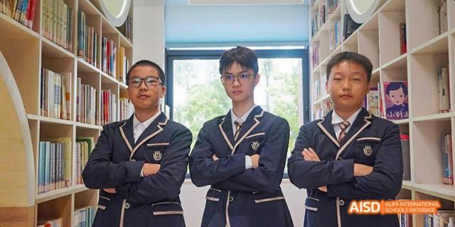 A group of Guangzhou Huamei International School students in uniform standing and posing outdoors, with the central student looking directly at the camera.