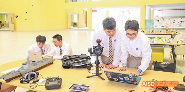 A Guangzhou Huamei International School teacher or student setting up a video camera on a tripod for a media or broadcasting class.