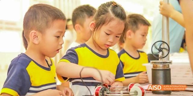 A young Guangzhou Huamei International School student focused on assembling a small project with wires and a battery.
