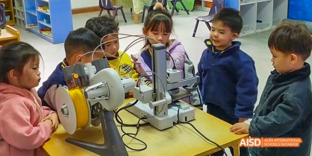 Young Guangzhou Huamei International School students collaborating on a science or engineering project using small laboratory equipment.