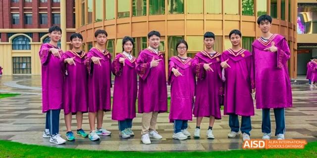 A group of graduating Guangzhou Huamei International School students in purple graduation gowns smiling and posing outdoors.