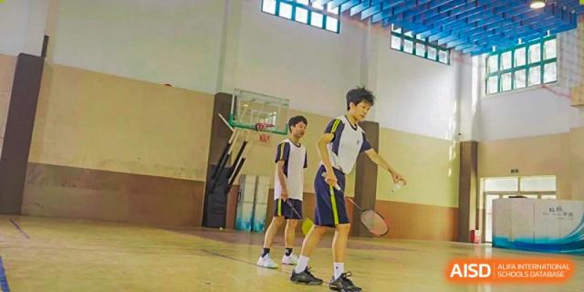 Guangzhou Huamei International School students playing badminton on a court, with a basketball hoop visible in the background.