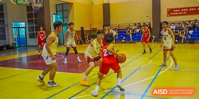 Two Guangzhou Huamei International School students playing basketball aggressively on the court during a game.