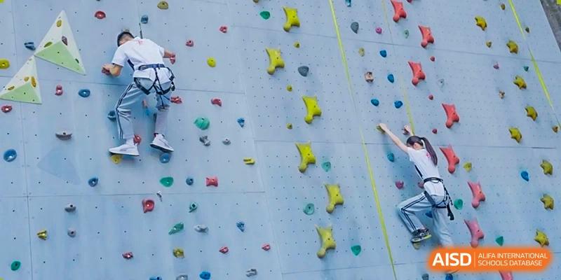 A rock climbing wall with various hand and foot holds at Guangzhou Huamei International School.