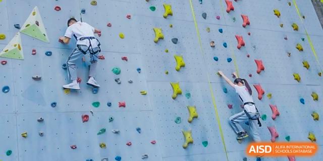 A rock climbing wall with various hand and foot holds at Guangzhou Huamei International School.