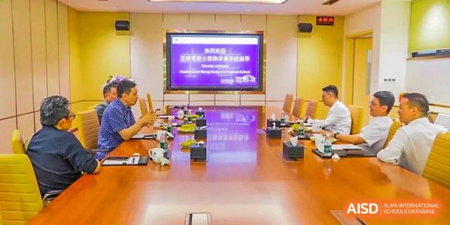 A large, modern conference room at Guangzhou Huamei International School with a long table and a screen displaying a presentation.
