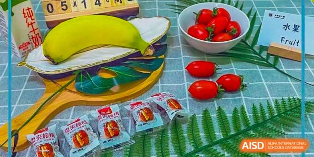 A colorful photo of fresh tomatoes, packets of food, and other fresh produce related to Guangzhou Huamei International School's nutrition program.