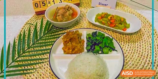 A balanced dinner plate served at Guangzhou Huamei International School, including rice, stir-fried chicken or meat, vegetables, and a bowl of soup.