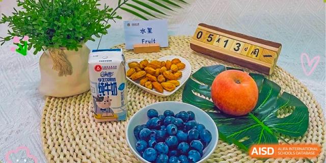A selection of fruit and nuts at Guangzhou Huamei International School, including a bowl of blueberries, a carton of milk, and almonds.