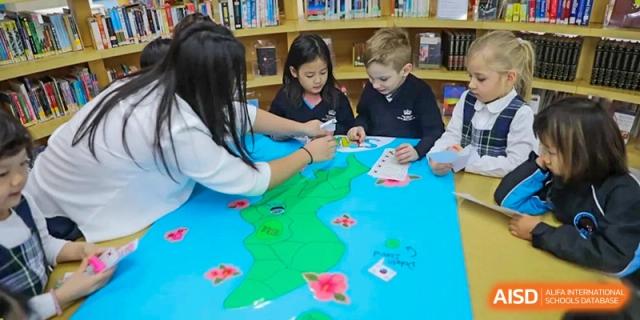 A photo showing a group of students in a classroom working on a world map, at The British School of Beijing, Shunyi.