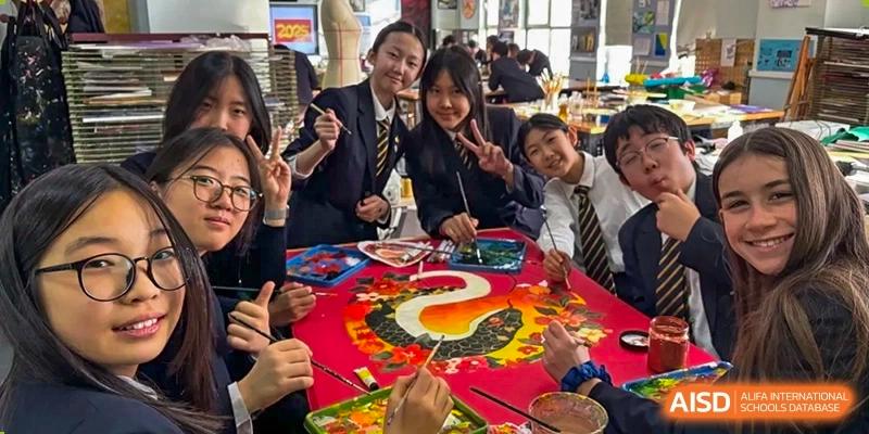 A photo showing students working on a painting on a table, at The British School of Beijing, Shunyi.