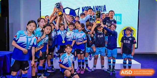 A photo showing a championship basketball team posing for a photo with a trophy, at The British School of Beijing, Shunyi.