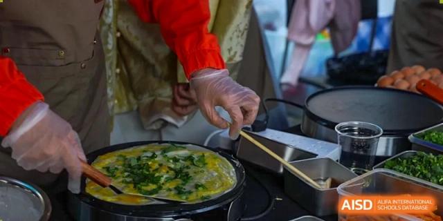 A photo showing a person cooking food in a pan, at The British School of Beijing, Shunyi.