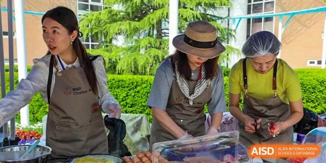 A photo showing a group of students and teachers preparing food, at The British School of Beijing, Shunyi.