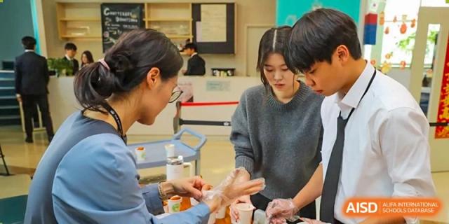 A photo showing a female student serving food to a male student, at The British School of Beijing, Shunyi.