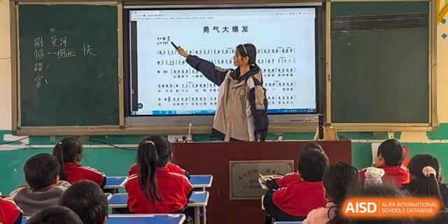A teacher at Zhengzhou No.9 High School International Department instructing students using a whiteboard in a classroom setting.