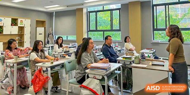 An Zhengzhou No.9 High School International Department classroom meeting or lecture with students and adults seated around a table.