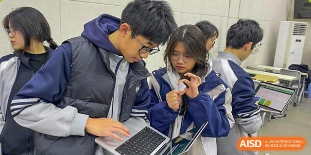 Two Zhengzhou No.9 High School International Department students collaborating on a laptop project during class.