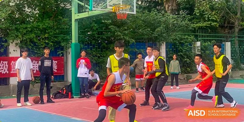 Students from Zhengzhou No.9 High School International Department playing basketball on an outdoor court.