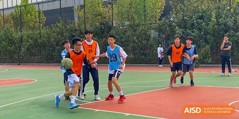 Students from Zhengzhou No.9 High School International Department playing soccer on a sports court.
