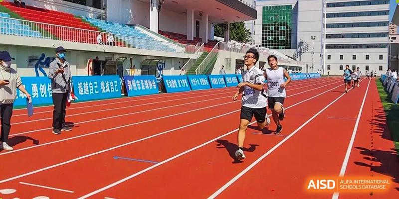 A Zhengzhou No.9 High School International Department student running on the red track of a sports stadium during an event.