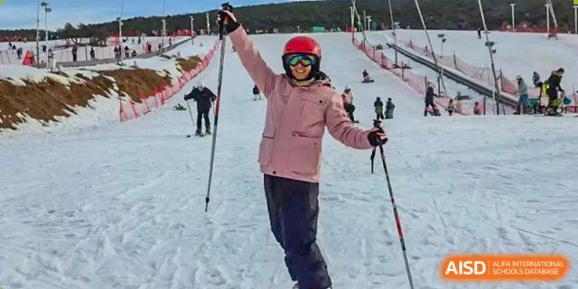A Zhengzhou No.9 High School International Department student smiling while skiing on a snowy slope.