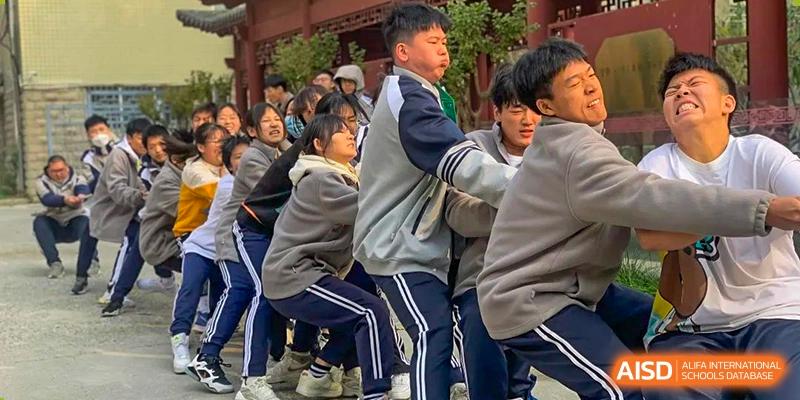Zhengzhou No.9 High School International Department students actively participating in a tug-of-war competition or team building exercise.