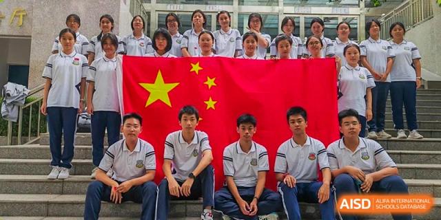 Zhengzhou No.9 High School International Department students posing in front of a large Chinese flag.