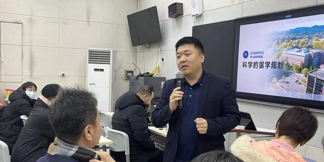 A speaker presenting with a microphone to an audience in a classroom at Zhengzhou No.9 High School International Department.