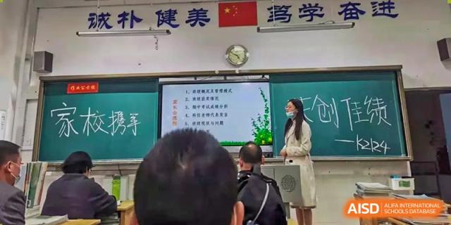 A teacher at Zhounan High School giving a lesson in front of a screen displaying a map of China.