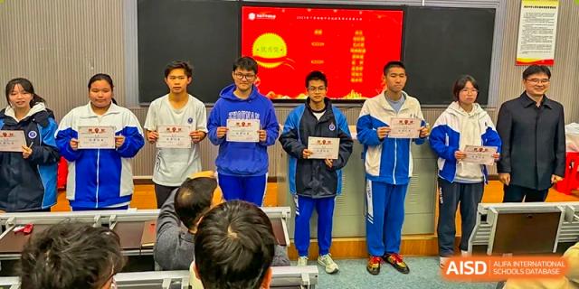 Two male students from Zhounan High School receiving certificates or awards in front of a red electronic display screen.