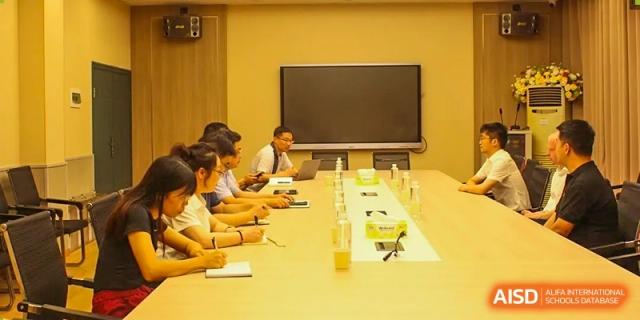 A meeting of faculty or staff from Zhounan High School seated around a conference table.