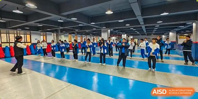 Zhounan High School students in uniform participating in an activity or formation inside a large indoor hall with a blue floor.