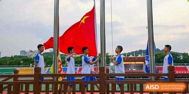 Students from Zhounan High School standing outdoors, holding a large red Chinese flag.