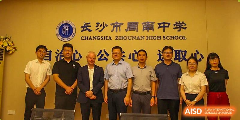 A group of male administrators or guests standing beneath a banner for "Changsha Zhounan High School," likely associated with the Zhounan High School.