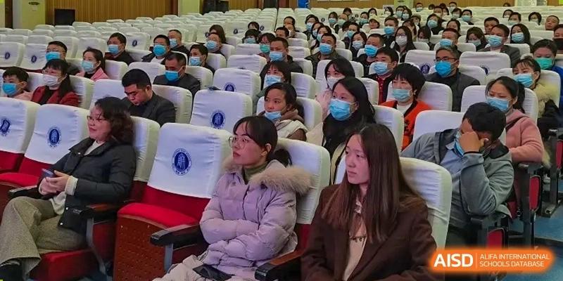 A wide shot of students from Zhounan High School attending an event or lecture in a large auditorium.