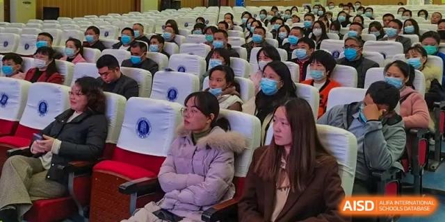 A wide shot of students from Zhounan High School attending an event or lecture in a large auditorium.