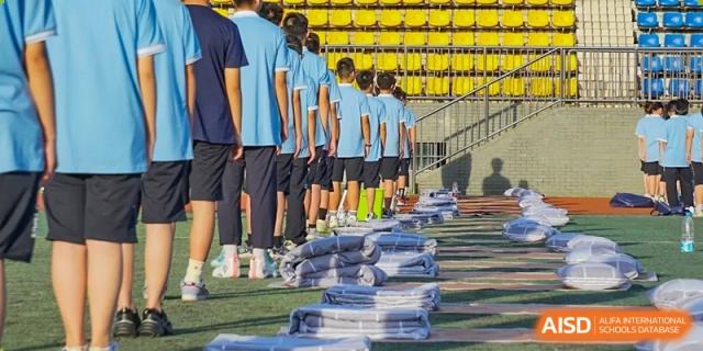 Students from Zhounan High School standing in formation on a sports field next to neatly stacked blue items.