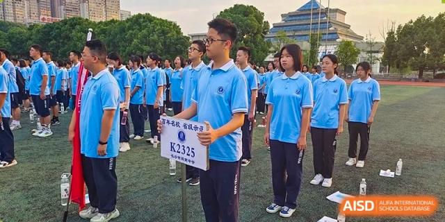 A male and female student from Zhounan High School in blue shirts standing in formation, with the male student holding a number placard.