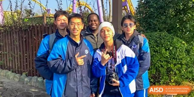 A group of Zhounan High School students and a teacher smiling for a photo, with some wearing blue and white jackets.