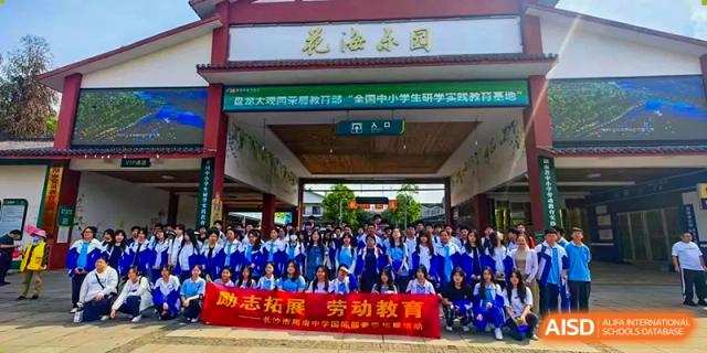 An exterior view of a school building entrance or hall at Zhounan High School with a red banner promoting labor education.