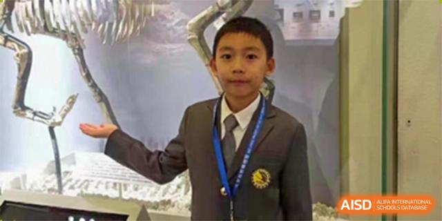A male student is wearing a school uniform and a tie, looking at the camera. Hangzhou Dipont School of Arts and Science.