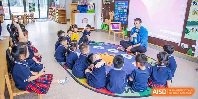 Young students are sitting in a circle on the floor, engaged in a group activity. Hangzhou Dipont School of Arts and Science.