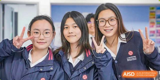 Two female students are smiling and posing for a picture, one making a peace sign. Hangzhou Dipont School of Arts and Science.
