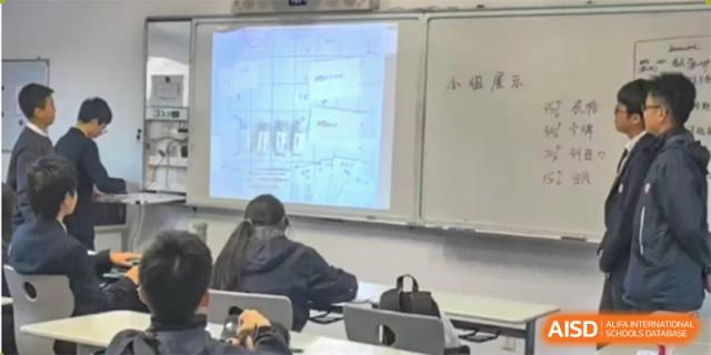 Students are seated in a classroom with a presentation on a large screen. Hangzhou Dipont School of Arts and Science.